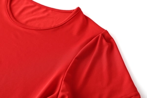 Dettaglio macro dell'abito rosso a girocollo con pieghe sulle spalle e cuciture fini