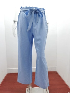 Detail of high-waisted paper-bag pants in light blue linen fabric with matching tie belt