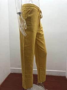 Detail view of yellow linen-blend trousers featuring a drawstring waist and side pockets
