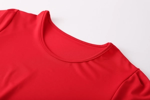 Gros plan d'un t-shirt rouge en tricot à col rond montrant des coutures précises