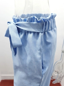 Close-up of light blue paperbag high waist with a self-tie bow on linen cotton trousers