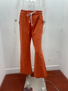 Detail view of orange linen wide-leg pants showing elastic waist and drawstring cord