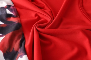 Dettaglio ravvicinato del tessuto in maglia rossa con stampe floreali astratte viola