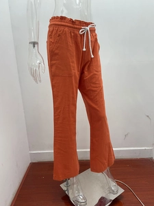 Detail of orange cotton linen pants featuring elastic drawstring waist and large pockets