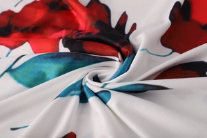 Détail macro du tissu en polyester doux avec imprimé floral rouge et feuilles vertes