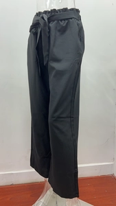 Detail of high waist paperbag elastic waistband with a decorative bow on black trousers