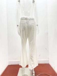Detail of white linen trousers showing high elastic waist with frill trim and back pockets