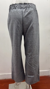 Detail of high waist grey linen trousers featuring elastic ruffle waistband and textured fabric