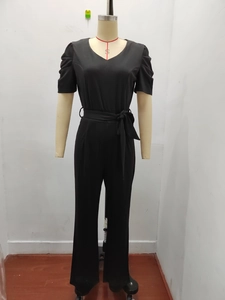 Detail of black V-neck jumpsuit showing cinched waist tie and ruched short sleeves