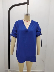 Dettaglio del top in chiffon blu reale con scollo a V e polsini annodati sulla manica
