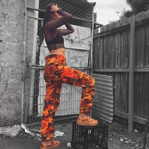 Dettaglio dei pantaloni cargo camouflage arancioni con tasche multiple e sneakers