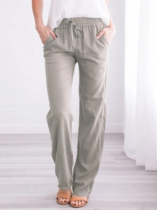 Detailed texture of drawstring waist and side pockets on light green cotton linen trousers