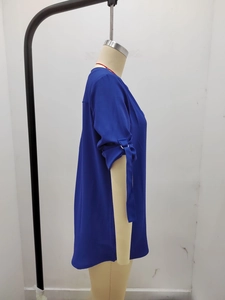 Dettaglio della camicetta in chiffon blu reale con fibbie metalliche sulle maniche