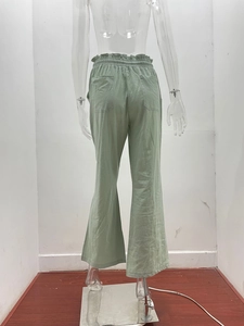 Detail of light green wide-leg trousers showing elastic ruffled waist and back pockets