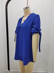 Dettaglio della camicetta in chiffon blu reale con scollo a V e polsini con laccetti