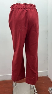 Rear view detail of high-waist loose linen trousers with elastic pleated waistband in dark red