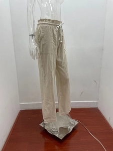 Detail of light beige linen pants showing elastic waistband, white drawstrings, and square pockets
