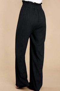 Detail of high-waisted elastic waistband with ruffled edges on black linen wide-leg pants