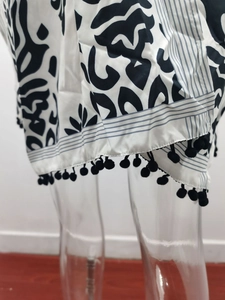 Détail du kimono avec motif vagues abstraites et bordure à pompons noirs décoratifs