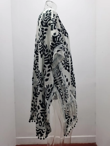 Détail du caftan bohème à fleurs noir et blanc avec franges à pompons et fente latérale