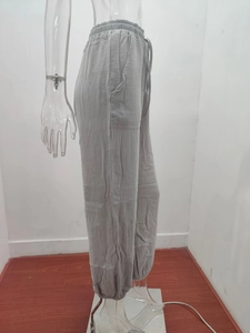 Detail of light grey joggers featuring elastic drawstring waist and textured fabric