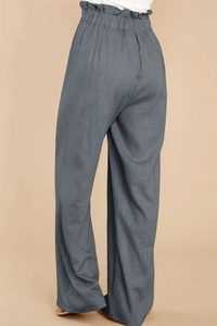 Detail view of the elastic paperbag waist and textured cotton-linen fabric on loose pants