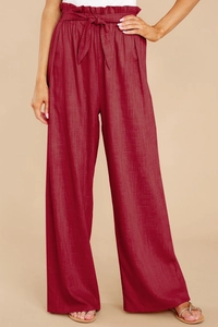 Detail of red high-waisted linen trousers with paperbag waist and matching tie belt