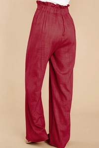 Detail view of high paperbag waist and texture on deep red linen wide-leg pants