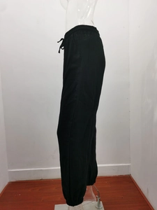 Detail of high-waisted black joggers featuring elastic drawstring waist and side pockets
