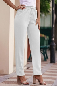 Detail of white cotton linen trousers featuring elastic drawstring waist and side pockets