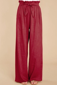 Detail of paperbag waist design on wide-leg burgundy cotton linen trousers with a bow tie
