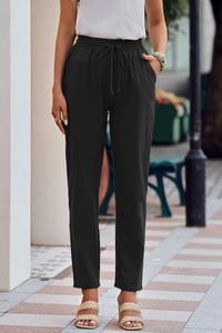 Detailed view of elastic drawstring waist and side pocket on black linen trousers