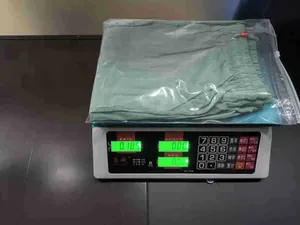 Détail d'un pantalon large en lin vert plié en sachet plastique transparent de taille S