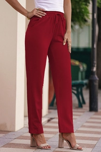 Detail view of high-waisted red linen trousers with drawstring waist and side pockets