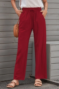 Detail of red wide-leg linen trousers with drawstring waist and functional side pockets