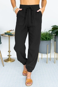 Detailed macro view of high-waist joggers showing black cotton linen fabric and drawstrings