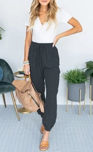 Detail of high waisted black joggers featuring elastic drawstring waist and side pockets