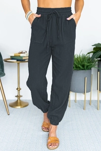 Detail of charcoal black high waist joggers with drawstring and textured linen fabric
