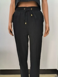 Détail de la taille élastique du pantalon en lin noir avec embouts de cordon dorés et œillets