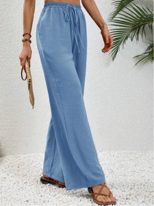 Dettaglio dei pantaloni a gamba larga celeste con coulisse regolabile e texture