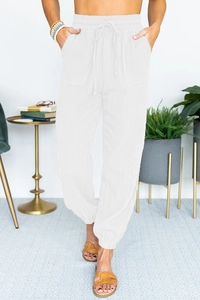Detail of high waisted white jogger pants with elastic drawstring waist and side pockets