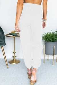 Detail view of white high-waisted joggers showing the elastic waistband and crepe texture