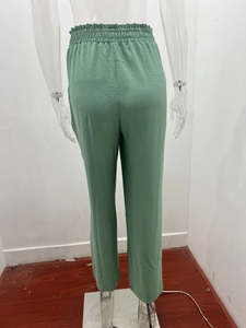 Dettaglio dei pantaloni a gamba larga verde salvia a vita alta in tessuto plissettato