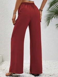 Vista posteriore dei pantaloni larghi a vita alta rosso ruggine in tessuto strutturato