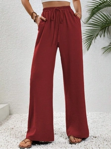 Dettaglio dei pantaloni larghi bordeaux con vita elastica a coulisse e trama a pieghe