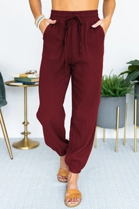 Detail view of burgundy high-waisted jogger pants with drawstring and ribbed texture