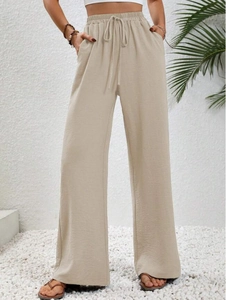 Dettaglio dei pantaloni larghi albicocca a vita alta con coulisse elastica e tasche laterali
