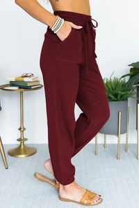 Detail of burgundy high waist jogger pants featuring drawstring and linen texture fabric