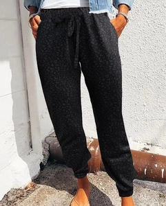 Detail of loose leopard print trousers with elastic drawstring waist and cinched ankles
