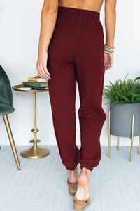 Rear view of dark red high-waisted jogger pants with elastic ankle cuffs and textured fabric